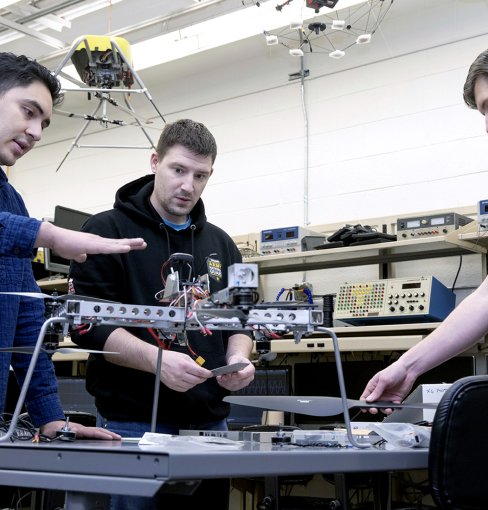 Three students working on a drone