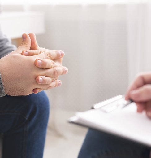 Therapist writing notes during counseling session with singl