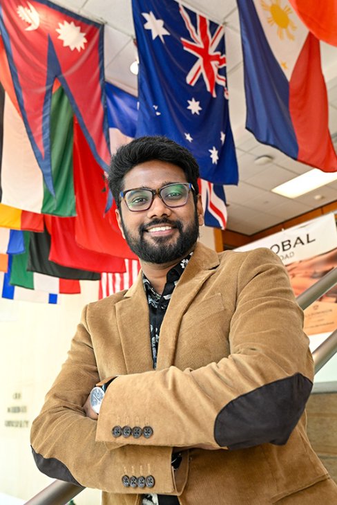Edward Moses standing under a display of international flags. 